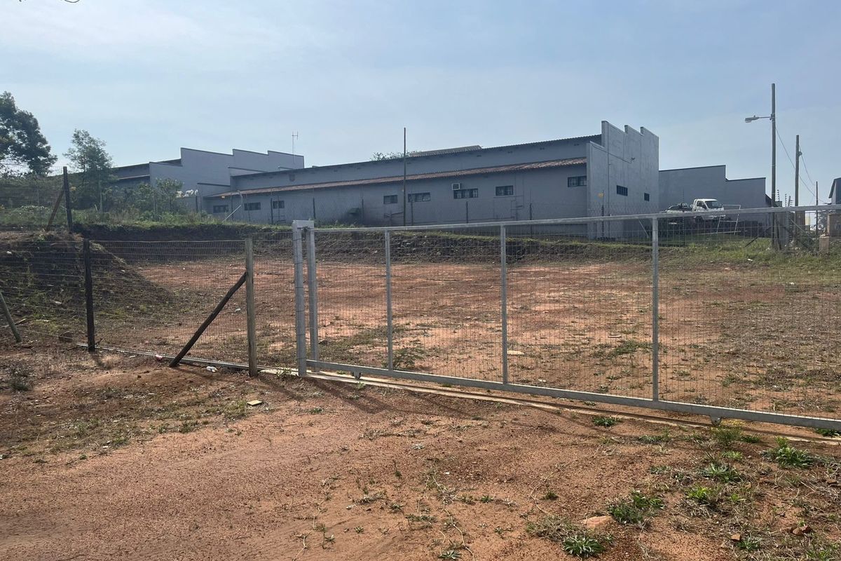 A vacant agricultural land plot featuring chain-link perimeter fencing and a metal sliding gate, providing clear access to the site.