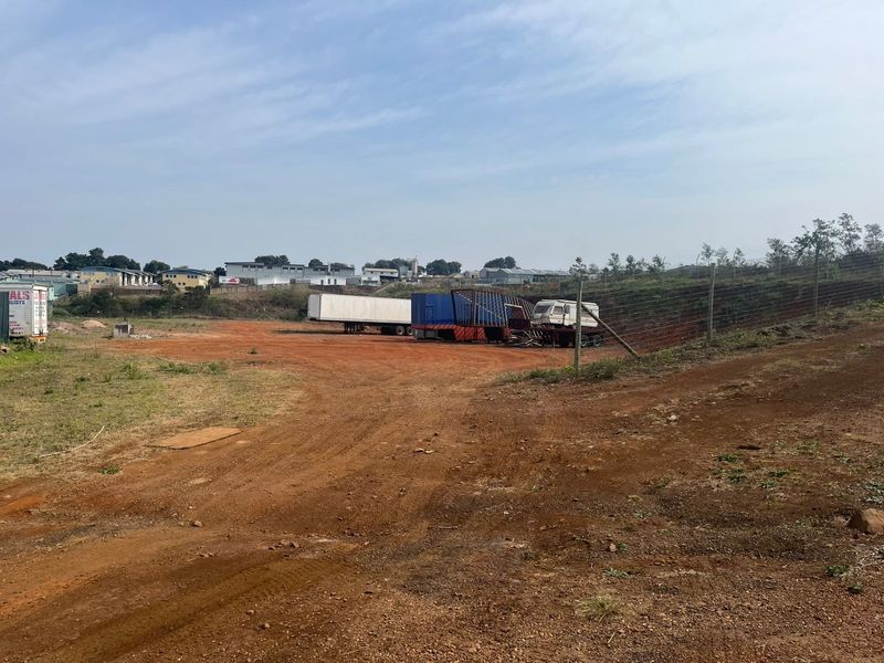 A view of the vacant agricultural land featuring open terrain and perimeter wire mesh fencing.
