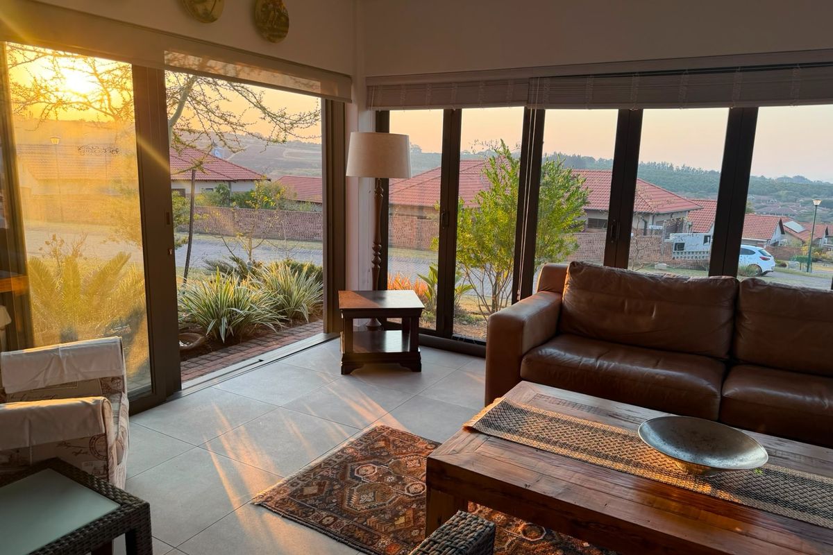 A bright living room featuring large aluminium sliding doors that provide ample natural light and views of the surrounding retirement village.