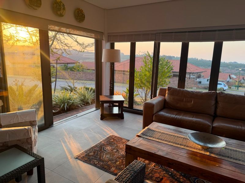 A bright living room featuring large aluminium sliding doors that provide ample natural light and views of the surrounding retirement village.