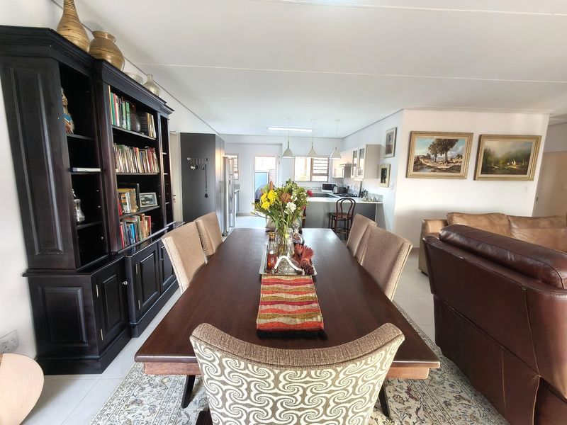 Spacious open-plan living and dining area featuring tiled floors, integrated kitchen cabinetry, and a central island, creating a functional and connected retirement living space.
