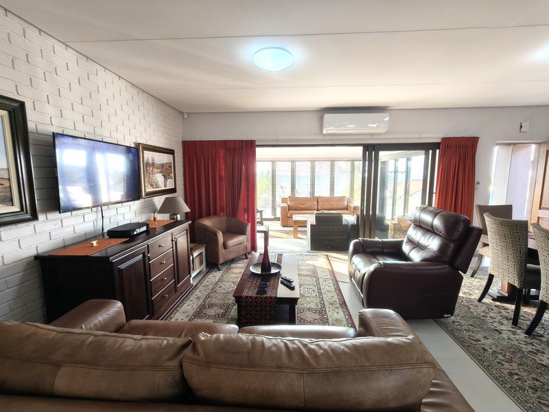 Spacious open-plan living area featuring a painted brick wall, split-system air conditioning, and large sliding glass doors leading to an enclosed patio.