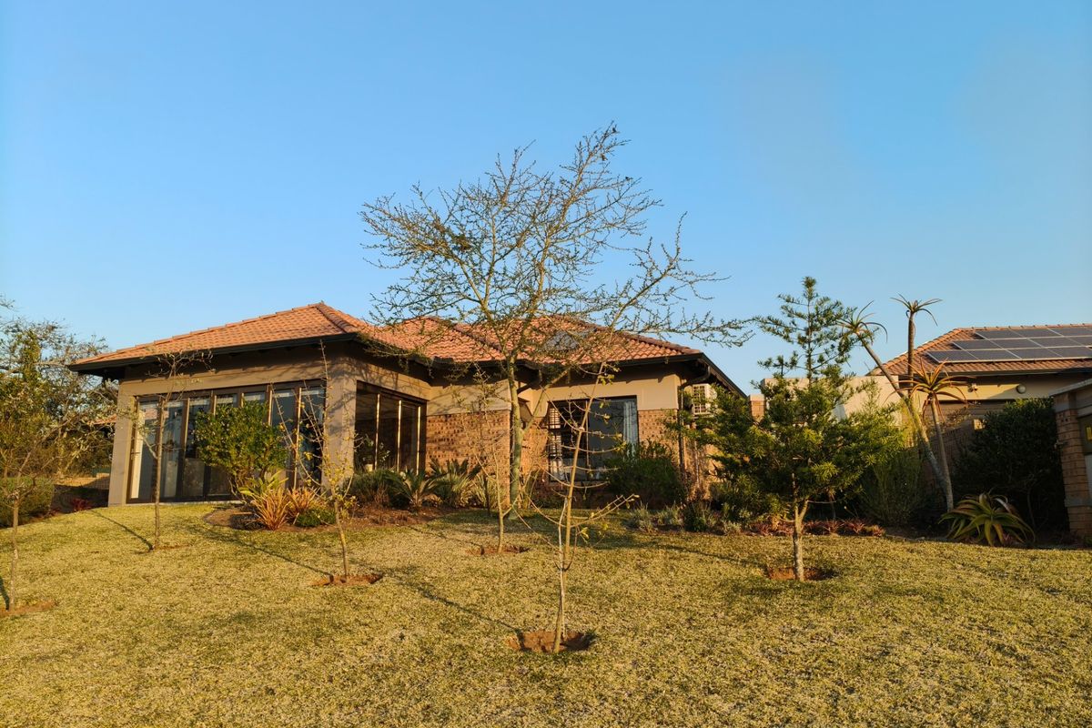 A well-maintained rear exterior view of a retirement village home featuring brick construction, terracotta roof tiles, and a landscaped garden.