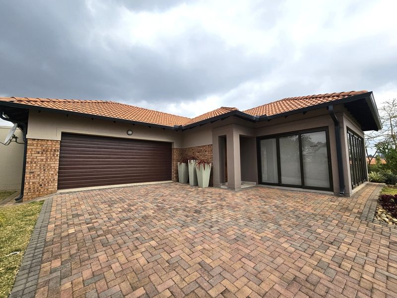 Front elevation of a retirement village home featuring a brick paved driveway, double garage, and covered entrance with terracotta roof tiles.