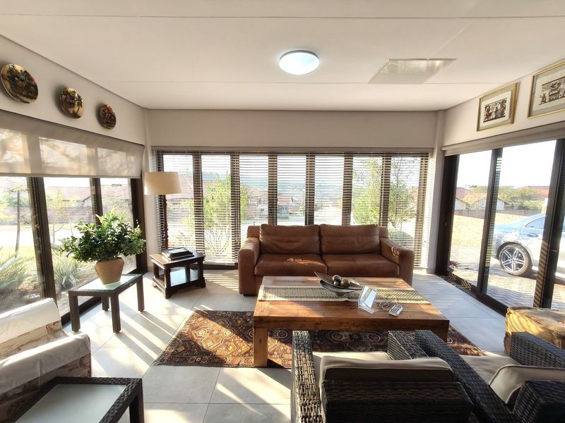 Bright and airy living room featuring large glass sliding doors, tiled flooring, and venetian blinds, offering a comfortable and well-lit space.