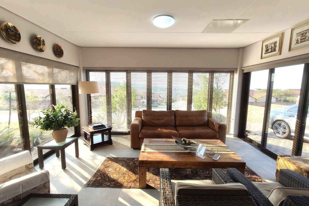 Bright and airy living room featuring large glass sliding doors, tiled flooring, and venetian blinds, offering a comfortable and well-lit space.