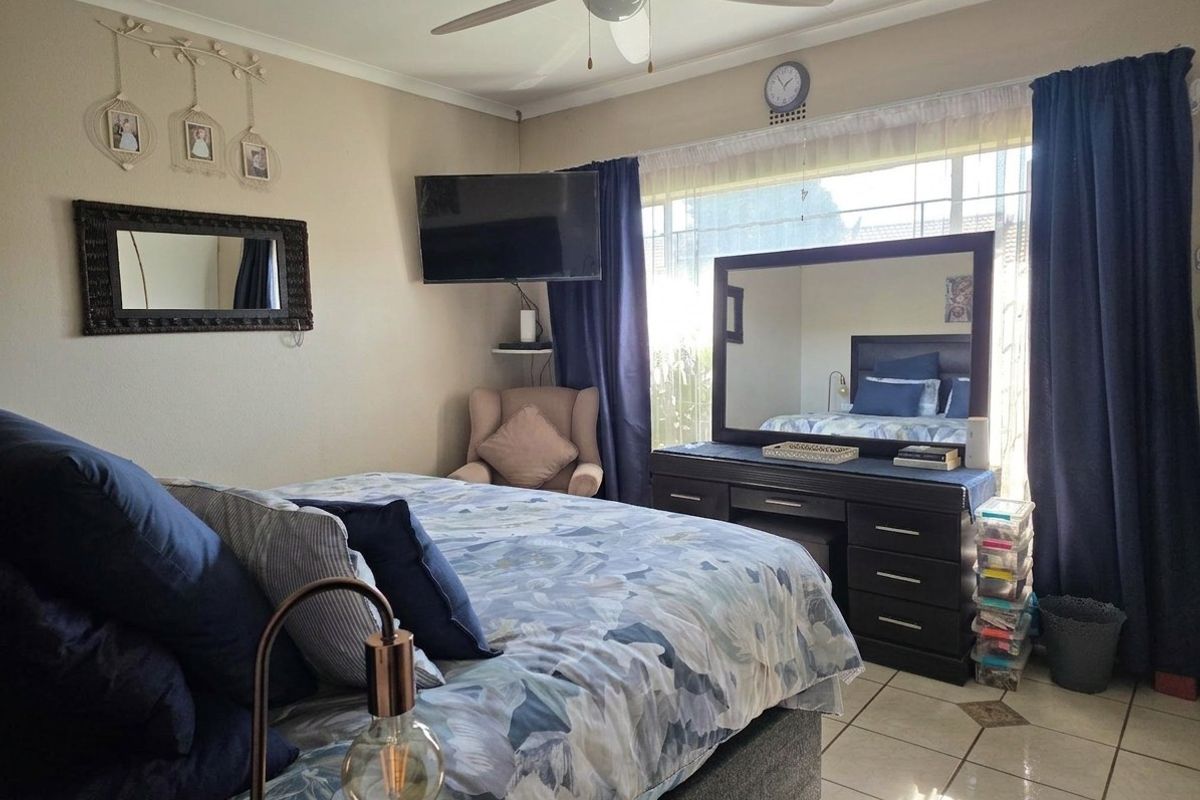 A bedroom featuring tiled flooring, a ceiling fan, and a large window allowing natural light into the space.