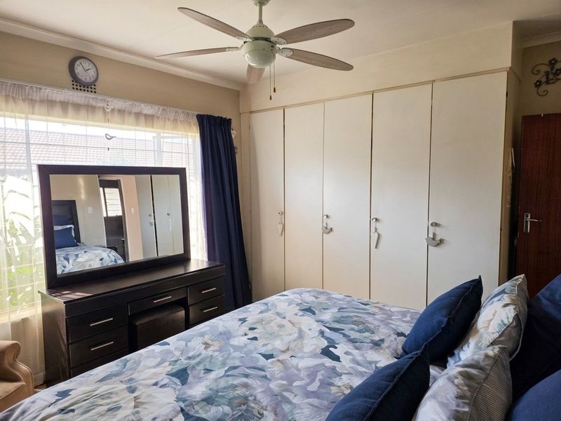 A bedroom featuring built-in cupboards and a ceiling fan, offering functional storage and climate control.