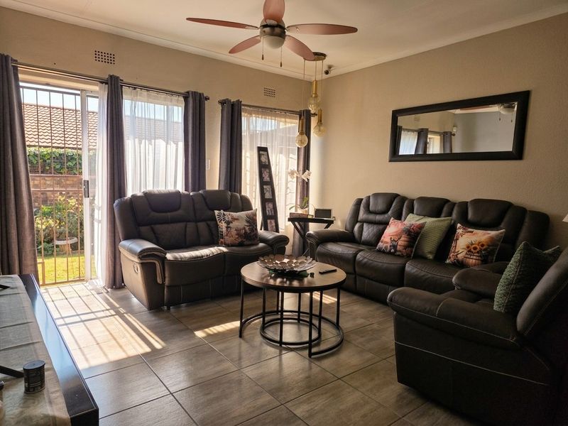 A comfortable living room featuring tiled flooring, a ceiling fan, and a sliding glass door providing direct access to the outdoor area.