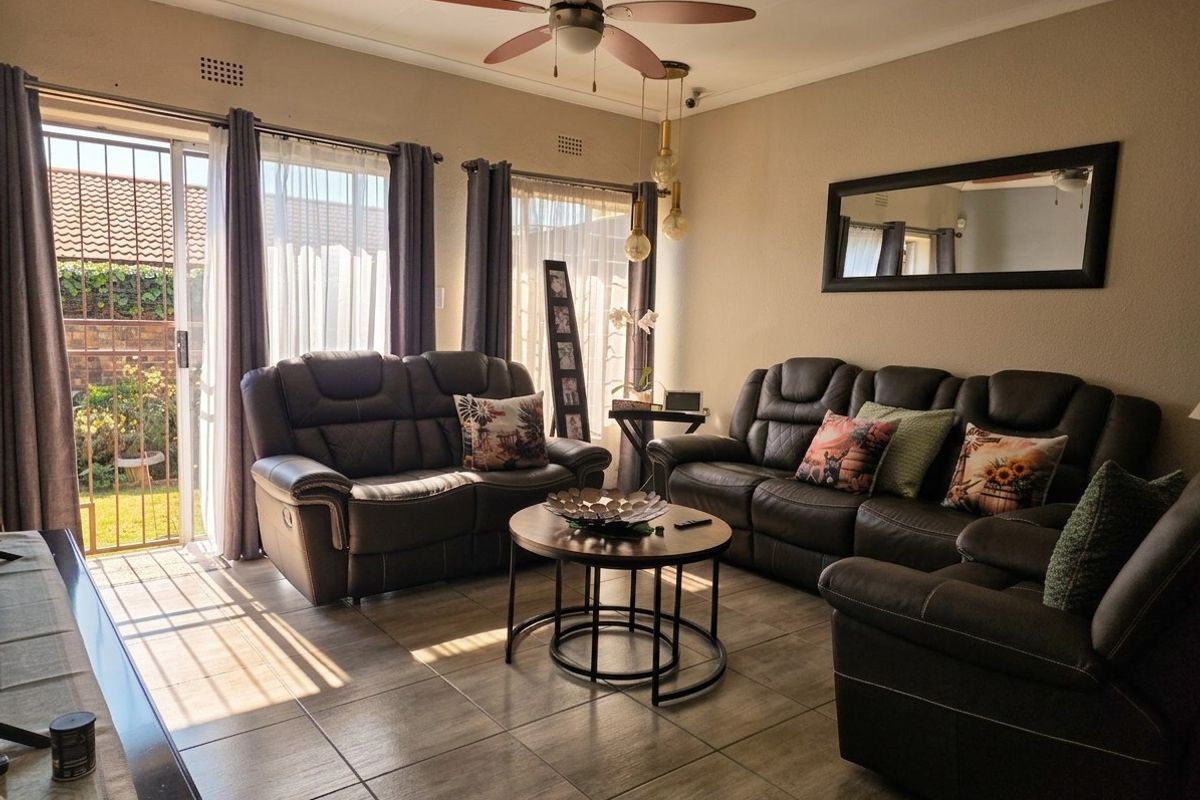 A comfortable living room featuring tiled flooring, a ceiling fan, and a sliding glass door providing direct access to the outdoor area.