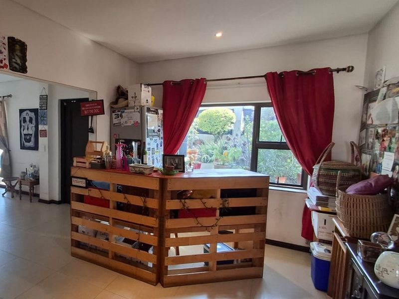 A living area featuring tiled flooring, recessed lighting, and a large window with garden views, offering a functional space for relaxation.