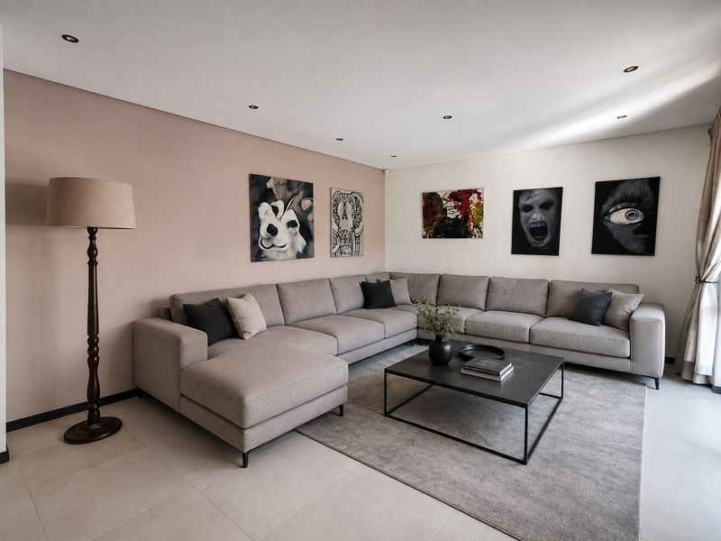 A modern, well-maintained living room featuring neutral tiled flooring, recessed downlighting, and a spacious layout with a feature accent wall.