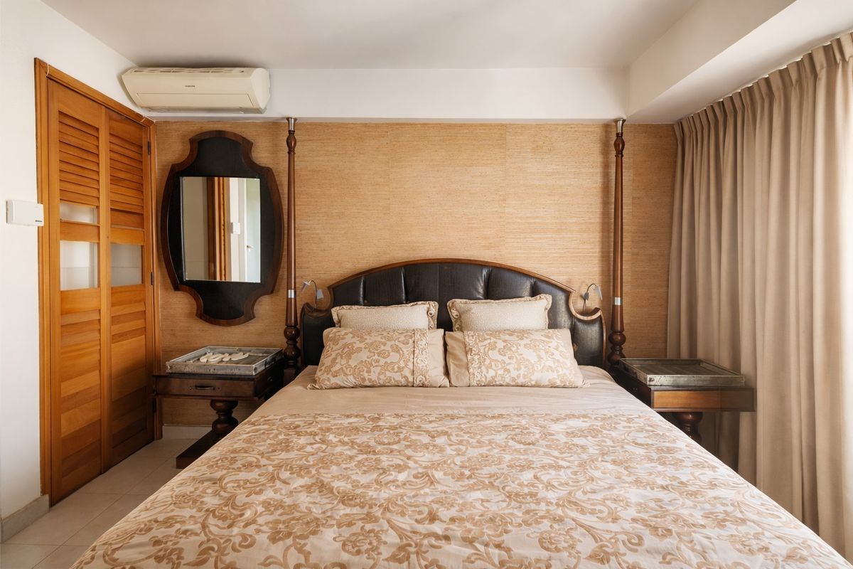 A well-maintained bedroom featuring textured wallpaper, louvered timber closet doors, and a wall-mounted split-system air conditioner.
