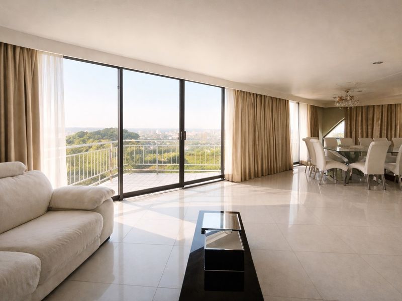 Spacious open-plan living and dining area featuring large sliding glass doors that open onto a balcony with expansive scenic views.