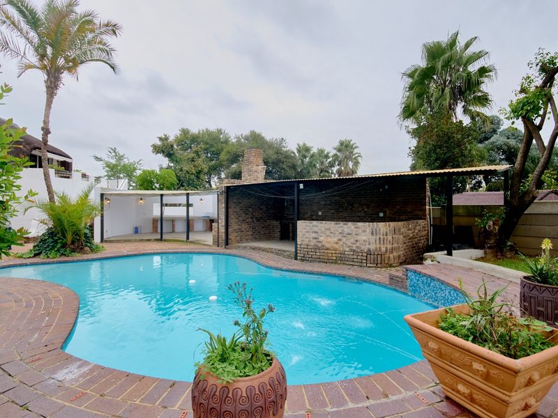 Outdoor entertainment area featuring a swimming pool, brick-built braai, and covered patio space, ideal for hosting and relaxation.
