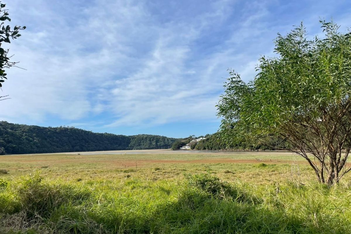 A scenic view of an open grassy landscape with surrounding hills and natural vegetation, showcasing the property's natural surroundings.