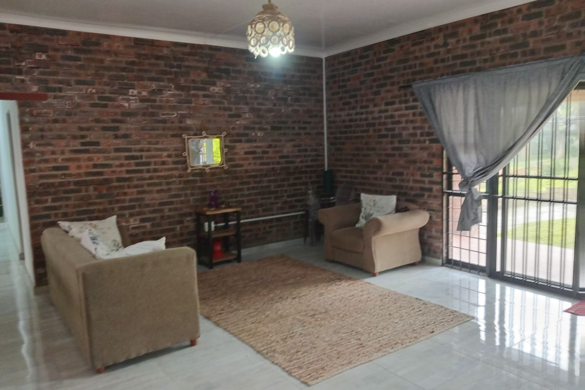 Living room featuring exposed brick walls, polished tiled flooring, and a large sliding glass door providing access to the exterior.