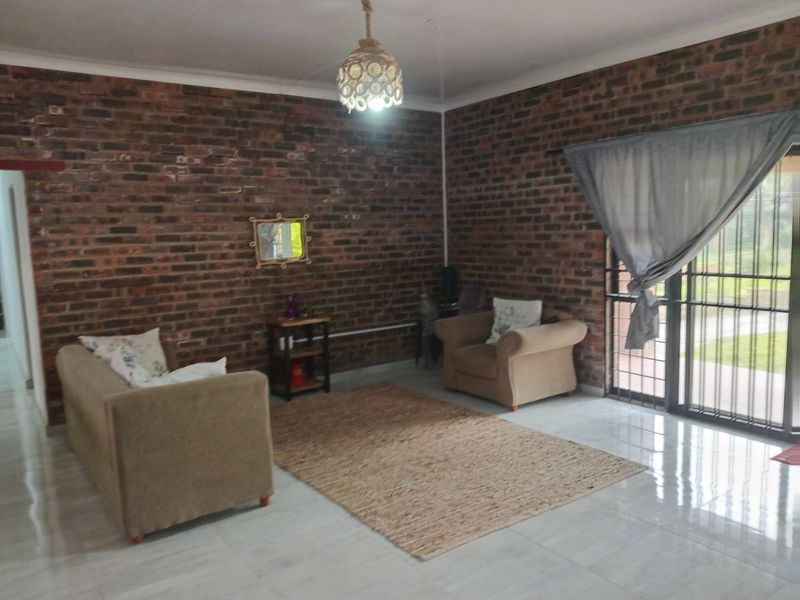 Living room featuring exposed brick walls, polished tiled flooring, and a large sliding glass door providing access to the exterior.