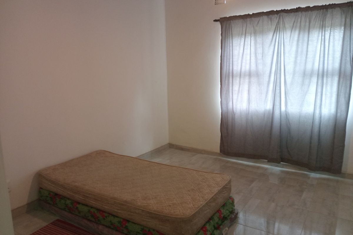 A simple, neutrally painted bedroom featuring tiled flooring and a window with curtains, offering a blank canvas for personalization.