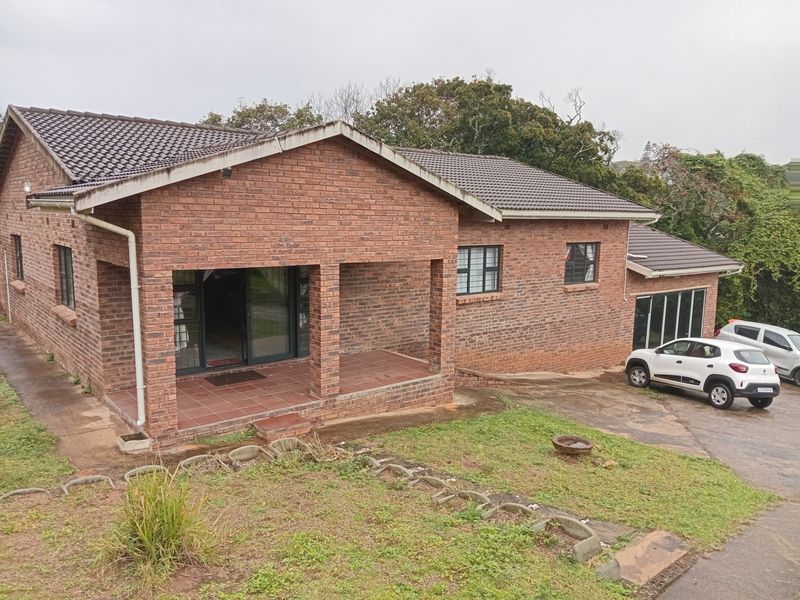 A single-story face brick house featuring a covered front patio, tiled roof, and a concrete driveway leading to the side of the property.