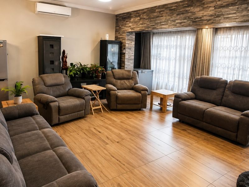 Spacious living room featuring modern tiled flooring, a stone veneer accent wall, and large sliding glass doors providing ample natural light.