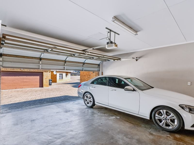 A functional single-car garage featuring concrete flooring, an automated sectional door, and overhead lighting.