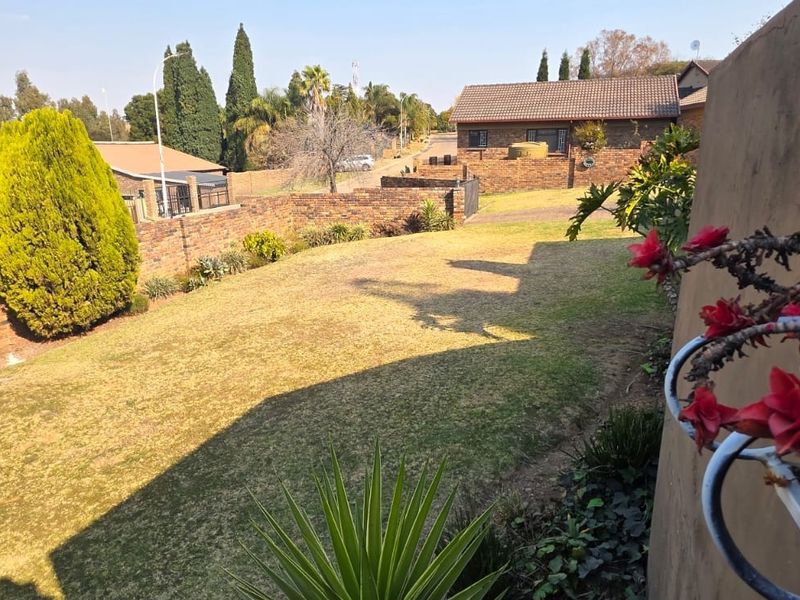 A spacious residential garden featuring a well-maintained lawn and established brick boundary walls, offering a private outdoor space.