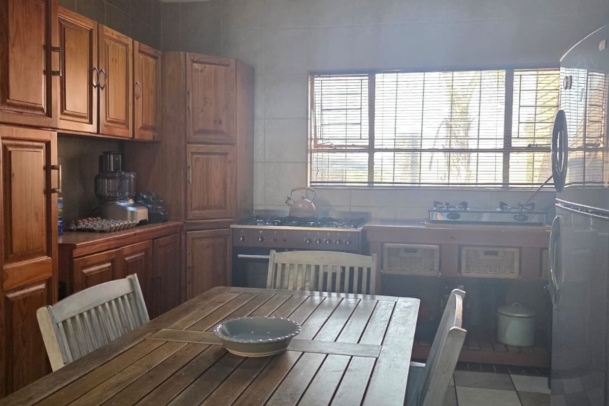 A functional kitchen featuring wooden cabinetry, a gas stove, tiled backsplash, and tiled flooring, offering a traditional aesthetic with practical storage and workspace.