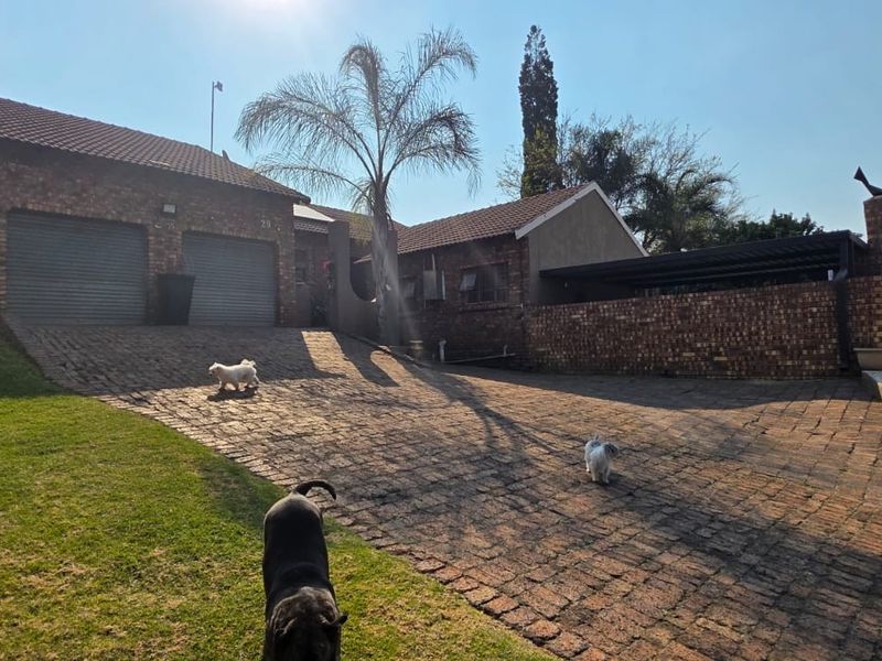 Front exterior view of a brick house featuring a double garage, paved driveway, and an attached carport.