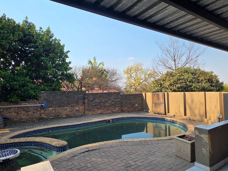 Outdoor pool area featuring a paved patio, covered veranda, and brick boundary walls, offering potential for a refreshed entertainment space.