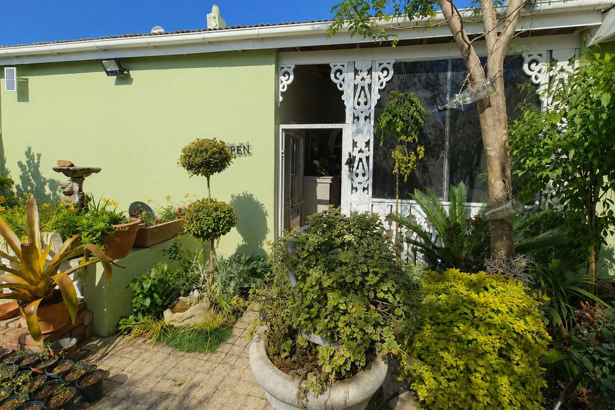A rear exterior view featuring a paved patio area, decorative timber fretwork detailing, and a security entrance door.