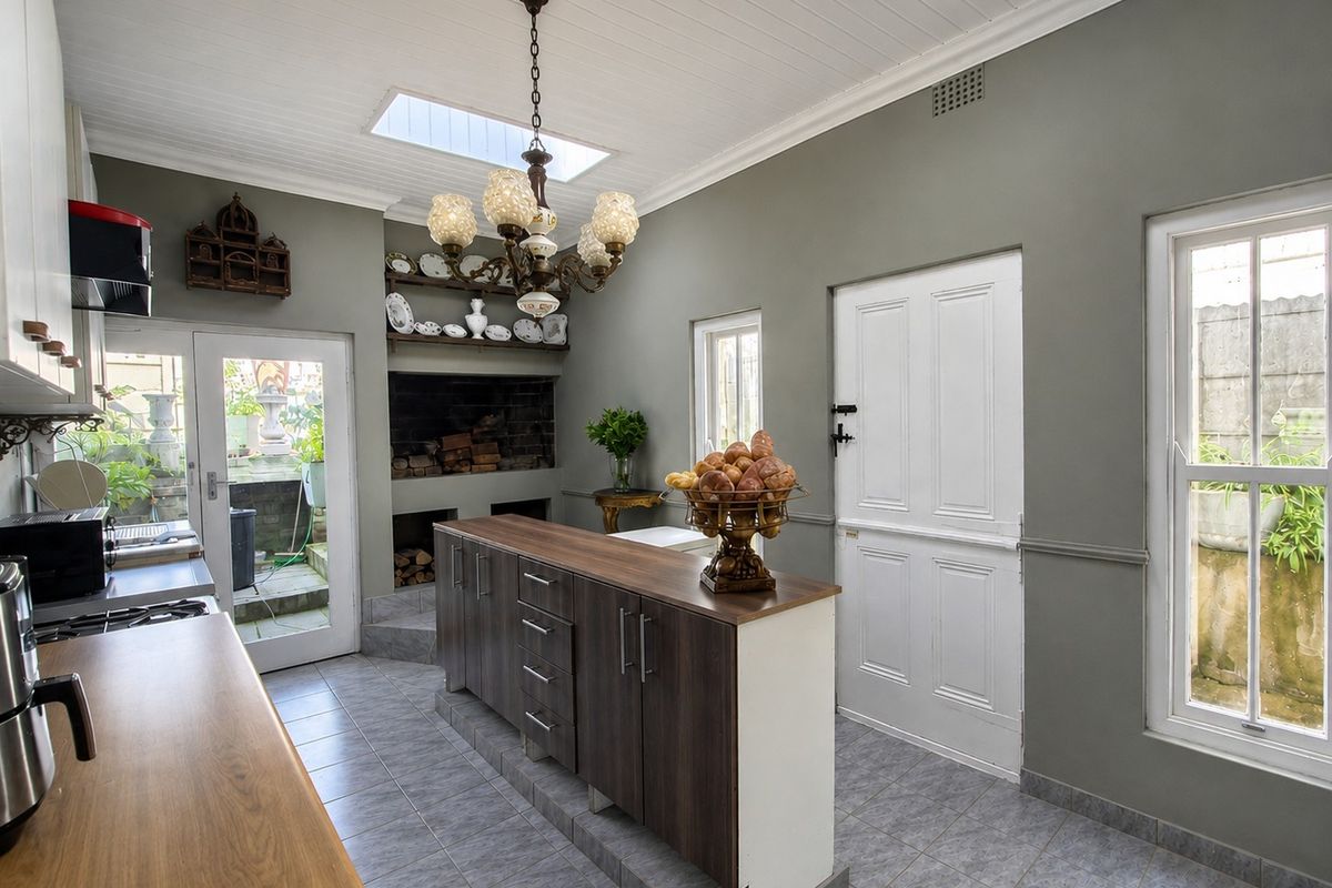 A well-lit kitchen featuring a central island, built-in fireplace, skylights, and direct access to the rear exterior through a stable door.