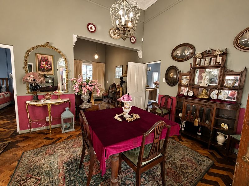 A formal dining room featuring classic parquet flooring, high ceilings with an ornate ceiling rose, and decorative wall paneling.