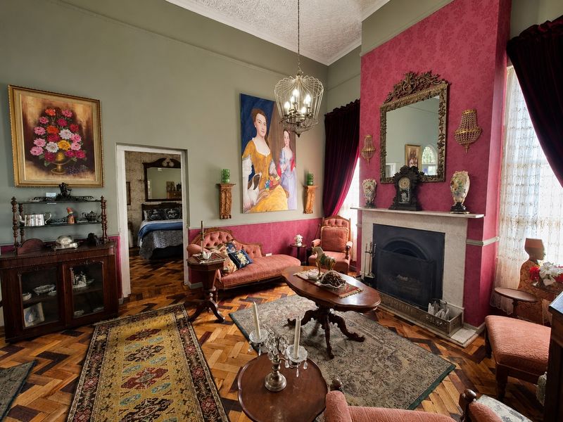 A character-filled living room featuring original parquet flooring, a traditional fireplace, and ornate ceiling detailing, offering a classic and historic aesthetic.