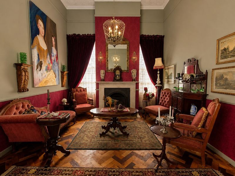 Elegant living room featuring a classic fireplace with marble mantelpiece, intricate herringbone timber flooring, and decorative crown molding with a ceiling rose.