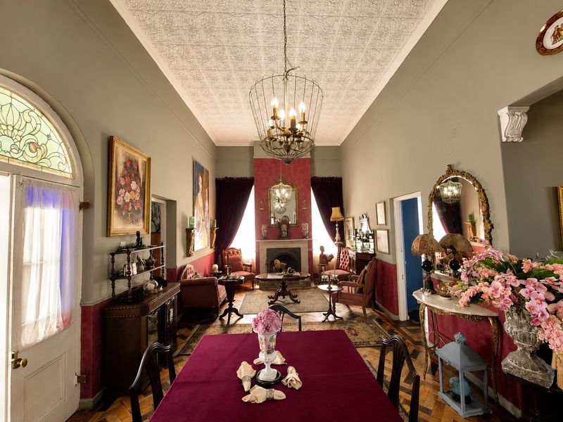 Elegant living room featuring a classic pressed metal ceiling, original parquet flooring, a central fireplace, and a beautiful arched stained glass window.