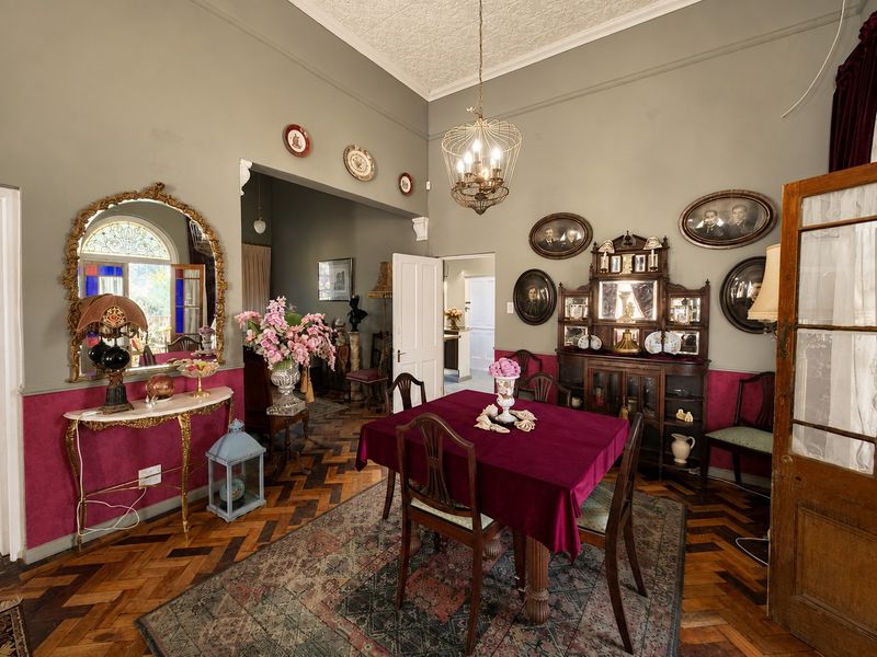 A formal dining room featuring classic herringbone parquet flooring, a decorative pressed metal ceiling, and an elegant archway leading to adjacent living spaces.