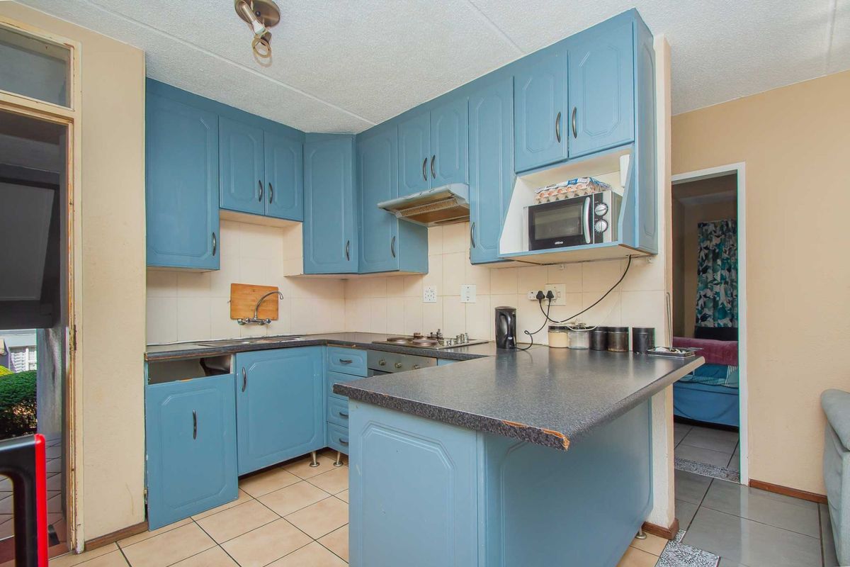 A dated kitchen featuring blue cabinetry, laminate countertops, and a built-in hob, offering potential for a modern renovation.
