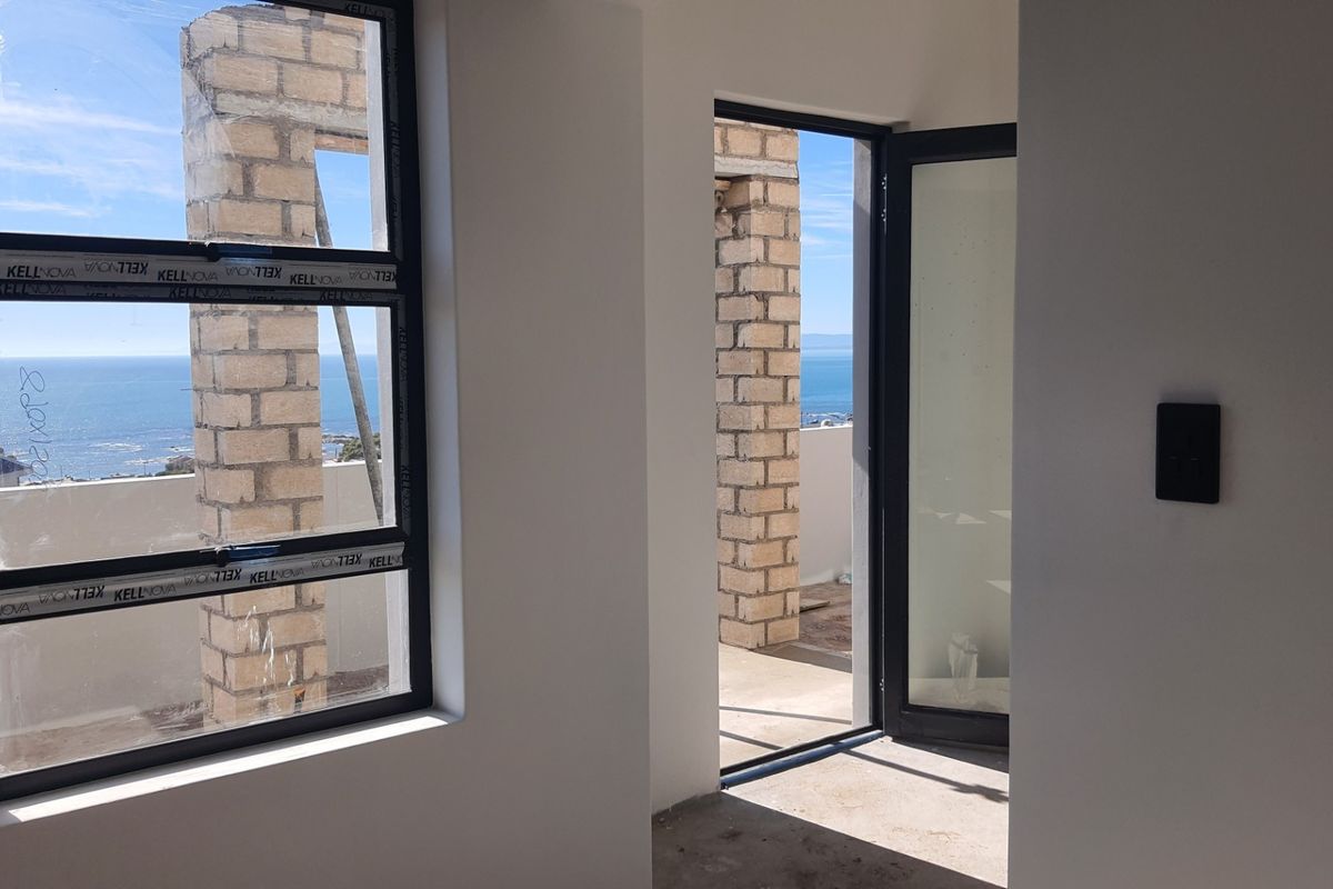 Unfinished bedroom interior featuring modern aluminium window and door frames with direct access to an outdoor balcony and ocean views.