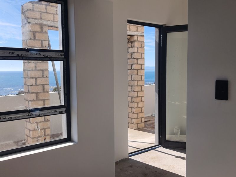 Unfinished bedroom interior featuring modern aluminium window and door frames with direct access to an outdoor balcony and ocean views.