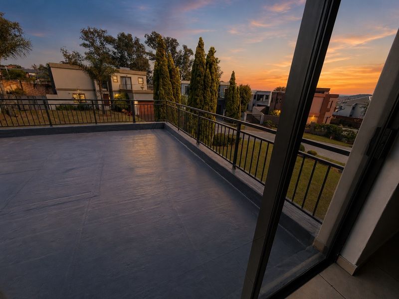 A spacious, elevated balcony featuring a durable waterproofed surface and metal balustrade, offering scenic sunset views over the surrounding residential estate.