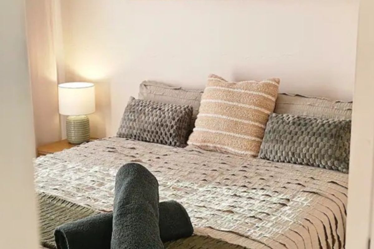 A cozy bedroom featuring neutral tones, tiled flooring, and soft overhead lighting, creating a comfortable and inviting sleeping space.