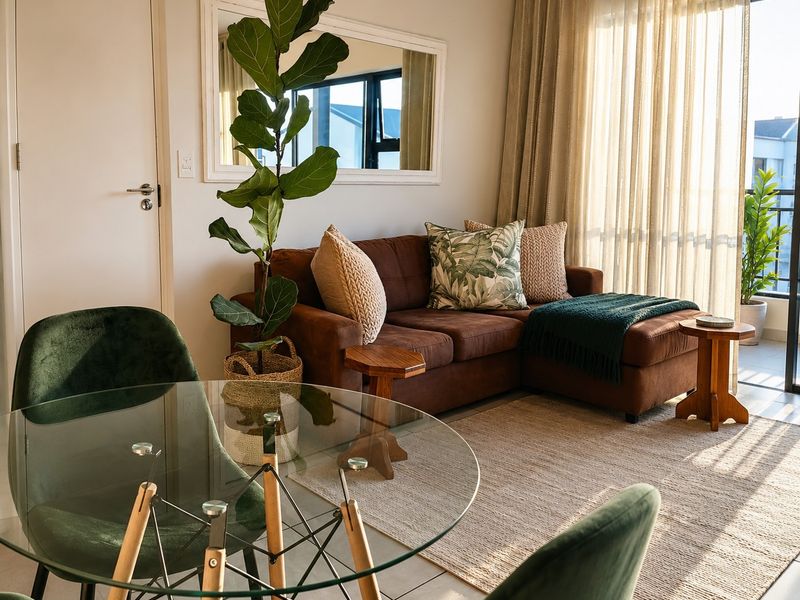 A bright open-plan living and dining area featuring tiled floors and large sliding glass doors that provide access to an outdoor balcony.