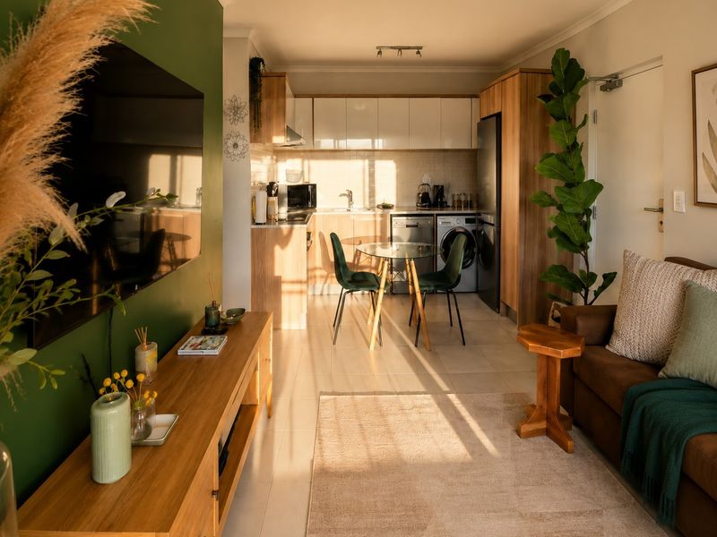 An open-plan living and kitchen area featuring modern cabinetry, tiled flooring, and a functional layout with integrated kitchen appliances.