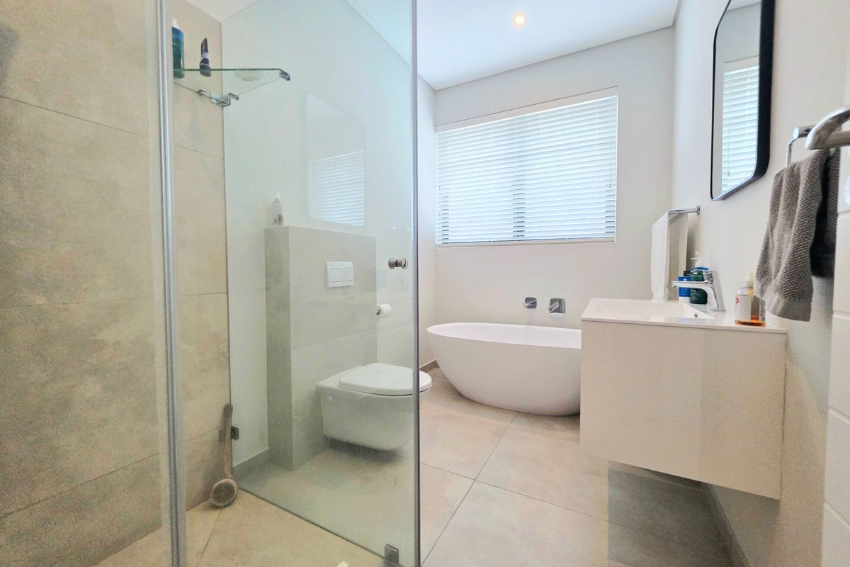 Modern bathroom featuring a freestanding bathtub, wall-hung toilet, walk-in shower with glass screen, and a sleek wall-mounted vanity.
