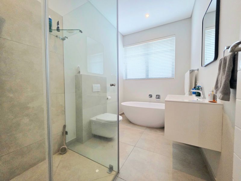 Modern bathroom featuring a freestanding bathtub, wall-hung toilet, walk-in shower with glass screen, and a sleek wall-mounted vanity.