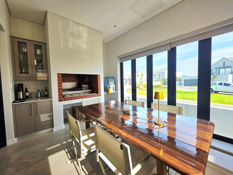 Modern dining area featuring a built-in brick braai, custom cabinetry, and large sliding doors providing ample natural light and views of the exterior.