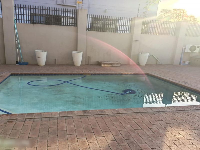Outdoor pool area featuring brick paving, perimeter wall with metal fencing, and an in-ground swimming pool.