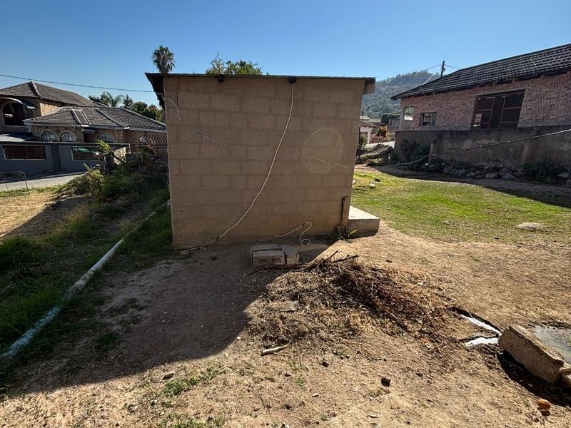 A view of the rear yard featuring an unfinished concrete block structure with exposed wiring and an unlandscaped outdoor area.