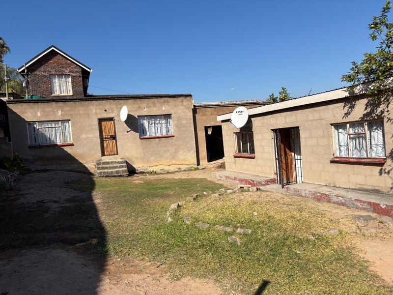 Rear view of the property showing multiple building sections, weathered plaster finishes, metal window frames, and a central courtyard area.